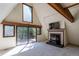 Bright living room with a fireplace and large windows offering views of the deck and lush greenery at 100 Aspen Ln, Evergreen, CO 80439