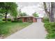 Charming single-story red brick home with a long driveway, lush green lawn, and mature trees at 3222 Fenton St, Wheat Ridge, CO 80212