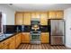 Well-lit kitchen featuring stainless steel appliances, wood cabinets, and black countertops at 2320 Morningview Ln, Castle Rock, CO 80109