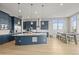 Bright, open kitchen featuring blue cabinetry, a large island with pendant lighting, and stainless steel appliances at 14341 Beebalm Loop, Parker, CO 80134