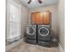 Well-lit laundry room featuring a front-load washer and dryer with built-in cabinets for ample storage at 2927 N Humboldt St, Denver, CO 80205