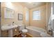 Bright bathroom with a pedestal sink, white tiled walls, and a glass block window above the tub at 461 N Marion St, Denver, CO 80218