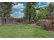 Backyard showcasing a well-maintained lawn, mature trees, and a wooden fence, offering privacy and a serene outdoor space at 9079 Garnet St, Highlands Ranch, CO 80126
