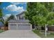 Two-story home features a two-car garage, well-maintained lawn, and mature trees in a tranquil residential setting at 9079 Garnet St, Highlands Ranch, CO 80126