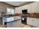 Modern kitchen featuring white cabinets, stainless steel appliances, and wooden accent wall, flooded with light at 9079 Garnet St, Highlands Ranch, CO 80126