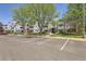Light blue condominium building with multiple units, balconies, parking area, and mature trees under a blue sky at 7665 E Eastman Ave # 106A, Denver, CO 80231