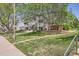 Exterior view of condo building surrounded by lush green lawns and mature trees on a sunny day at 7665 E Eastman Ave # 106A, Denver, CO 80231