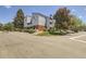 Corner view of light blue condo building with brick accents, landscaped gardens, and designated parking spaces at 7665 E Eastman Ave # 106A, Denver, CO 80231