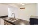Functional kitchen with black countertops, stainless steel sink, and view to the living room at 7665 E Eastman Ave # 106A, Denver, CO 80231