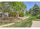 Landscaped side yard with brick foundation, lush greenery, rock pathway, and mature trees for a serene outdoor setting at 7665 E Eastman Ave # 106A, Denver, CO 80231