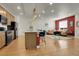 Bright living room with modern kitchen, island seating, hardwood floors, and red accent wall at 16818 E 119Th Ave # A, Commerce City, CO 80022