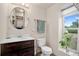 Bathroom features a dark wood vanity, rounded mirror, neutral walls, and a window with leafy green plant at 2773 S Lansing Way, Aurora, CO 80014
