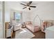 Bright bedroom with a charming white house frame bed, plush chair, ceiling fan and a window view at 1049 Lilac St, Broomfield, CO 80020