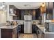 Bright kitchen featuring dark wood cabinets, stainless appliances, tile backsplash, and granite countertops at 1049 Lilac St, Broomfield, CO 80020