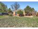 A brick home with green grass and trees in the front yard at 2220 Quebec St, Denver, CO 80207