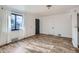 Bright living room with wood-look floors, white walls, and a large window with sheer curtains at 2220 Quebec St, Denver, CO 80207