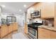 Well-lit kitchen featuring stainless steel appliances, light wood cabinets, and stylish countertops at 11 S Albion St, Denver, CO 80246