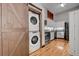 Open kitchen area showcasing a stackable washer and dryer behind a barn door, with stainless appliances and hardwood floors at 720 16Th St # 421, Denver, CO 80202