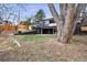 Backyard view showing exterior of home with sunroom, covered patio and landscaped yard with mature tree at 6948 W 70Th Ave, Arvada, CO 80003