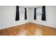 Empty bedroom featuring hardwood floors, two large windows with blackout curtains, and neutral walls at 6948 W 70Th Ave, Arvada, CO 80003