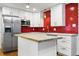 Bright kitchen featuring an island, stainless steel appliances, white cabinets, and red tile backsplash at 6948 W 70Th Ave, Arvada, CO 80003