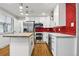 Bright kitchen featuring an island, stainless steel appliances, white cabinets, and red tile backsplash at 6948 W 70Th Ave, Arvada, CO 80003