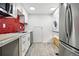 Modern kitchen with stainless steel appliances, a striking red tile backsplash, and durable vinyl plank flooring at 6948 W 70Th Ave, Arvada, CO 80003