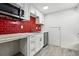 Well-lit kitchen features red tile backsplash, stainless sink and faucet, and vinyl floors, a harmonious blend of style at 6948 W 70Th Ave, Arvada, CO 80003