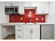 Bright kitchenette features stainless steel appliances, white cabinetry and a bold red backsplash at 6948 W 70Th Ave, Arvada, CO 80003