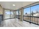 An indoor/outdoor sunroom with wood-look floors, full-length windows and views of a fenced yard and surrounding neighborhood at 6948 W 70Th Ave, Arvada, CO 80003