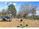 A sunny community playground features colorful equipment, including slides and swings, and mature trees at 2500 S York St # 410, Denver, CO 80210