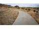 A smooth concrete walking path leading towards a grassy hilltop with neighborhood views at 8791 Culebra Ct, Arvada, CO 80007