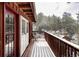 Scenic deck with wood railing, offering views of the surrounding pine trees and snow-covered landscape at 26288 S End Rd, Kittredge, CO 80457