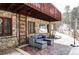 Stone patio with comfortable seating, showcasing the stone exterior of the home and snowy surroundings at 26288 S End Rd, Kittredge, CO 80457