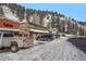 A snow-lined street view shows shops with awnings and parked cars nestled against a hillside with evergreen trees at 26288 S End Rd, Kittredge, CO 80457