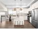 Bright, modern kitchen features stainless steel appliances, white cabinetry, island with seating, and hardwood floors at 5360 Allison St # D, Arvada, CO 80002