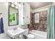 Bathroom featuring a sink, white cabinet, toilet and shower with brown tile at 4433 S Washington St, Englewood, CO 80113