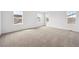 Large bedroom featuring neutral carpet, white walls, and multiple windows for natural lighting at 45952 Gentry Ave, Bennett, CO 80102