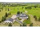 Stunning aerial view of the charming home with a separate garage surrounded by a vast green field at 3973 Palmer Ridge Dr, Parker, CO 80134