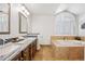 Bright bathroom featuring double sinks, granite countertop, bathtub, and tiled floor at 9025 Rocky Mountain Ln, Parker, CO 80138