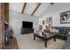 Comfortable living room with brick fireplace, large tv, wood beams and access to dining area at 9025 Rocky Mountain Ln, Parker, CO 80138
