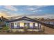 Well-lit exterior of a charming gray home, highlighting its inviting entrance at dusk at 13619 Lake Ave, Brighton, CO 80603