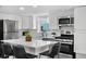 Modern white kitchen with stainless steel appliances, a quartz island, and black leather barstools at 13619 Lake Ave, Brighton, CO 80603