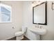 Charming powder room featuring pedestal sink, dark wood floors, framed mirror, and natural light from a window at 14391 Shasta Daisy Pt, Parker, CO 80134