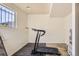 This basement area features a modern treadmill in front of a bright window and white painted brick at 18890 E Carmel Cir, Aurora, CO 80011