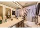 Well-lit bathroom featuring a vanity with storage and a shower with a decorative curtain at 18890 E Carmel Cir, Aurora, CO 80011