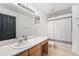 Neutral bathroom with wood vanity, large mirror, and shower with white curtain at 13275 Holly St # B, Thornton, CO 80241