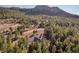 An aerial shot of a luxury home surrounded by a dense forest and winding mountain roads at 6016 Stone Creek Dr, Evergreen, CO 80439