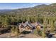 Expansive home surrounded by lush trees, set against a backdrop of mountain views at 6016 Stone Creek Dr, Evergreen, CO 80439