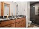 Bathroom showcasing double vanity with granite countertop, wood cabinetry, and a modern glass enclosed shower at 6016 Stone Creek Dr, Evergreen, CO 80439